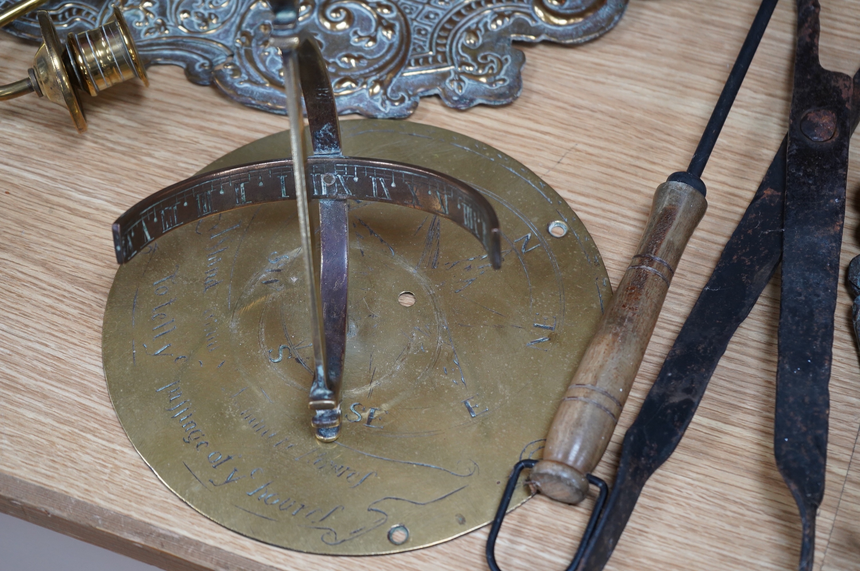 A pair of brass repousse wall sconces, a copper two handle mug, a small brass sun dial, a pair of tongs and a roasting trivet. Condition - poor to fair
